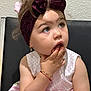 Leya is registered to the contest to win money with this photo: child, toddler, girl, headband, purple_bow, dress, pink, polka_dot, bracelet, curly_hair, earrings, sitting, indoor, cute, expression, face, hand, young, portrait, thoughtful