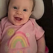 Hailey is registered to the contest to win money with this photo: apparel, baby, child, clothing, cushioned_seat, cute, expression, face, happy, head, indoor, infant, joyful, person, pink_shirt, portrait, rainbow, smiling, sun, young