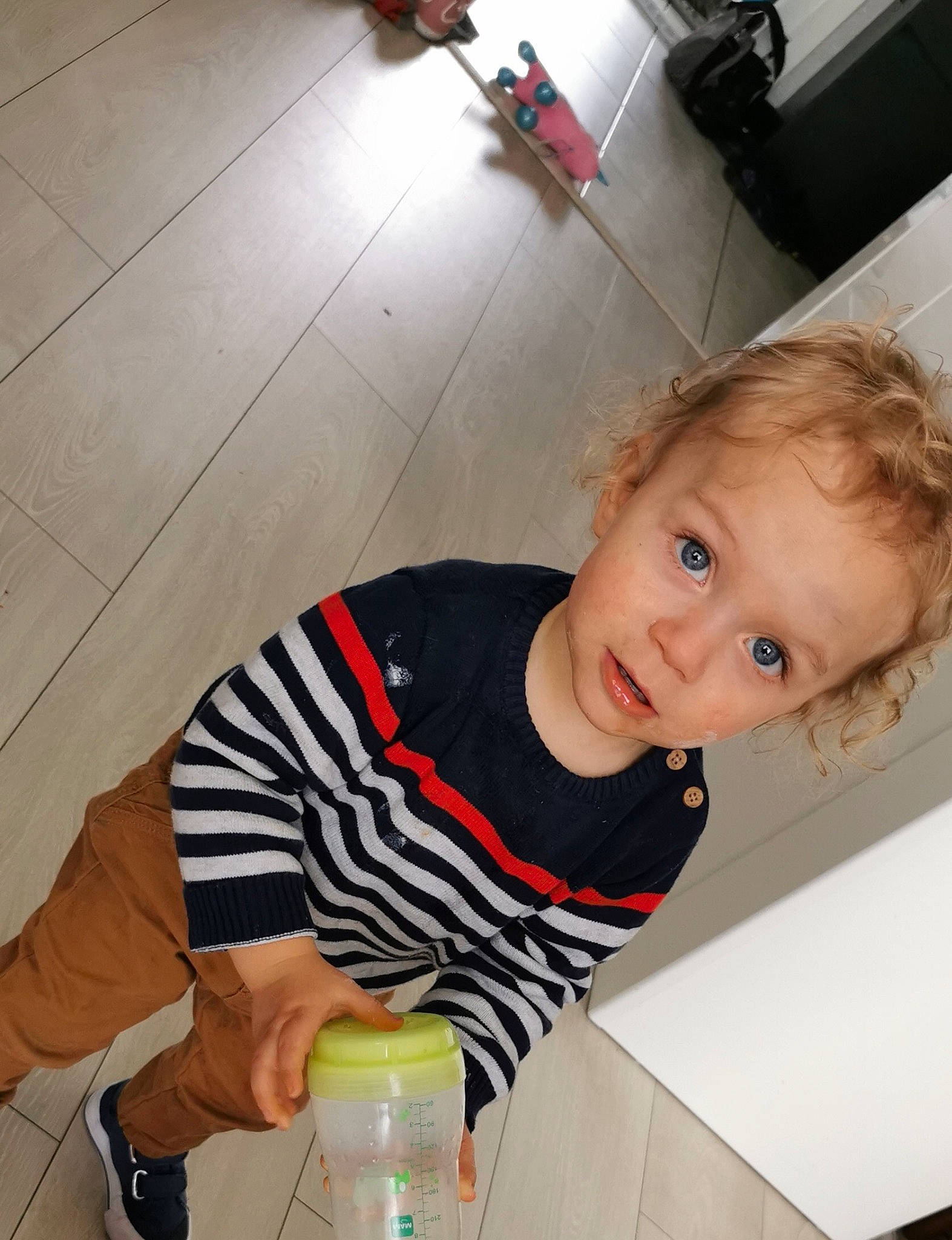 Adélino a rejoint le concours — aidez-le/la à gagner de superbes lots ! baby_toddler_clothing, bottle, child, elbow, finger, floor, flooring, fun, hairstyle, joint, knee, person, plastic_bottle, sleeve, smile, t_shirt, thigh, toddler, water_bottle, white