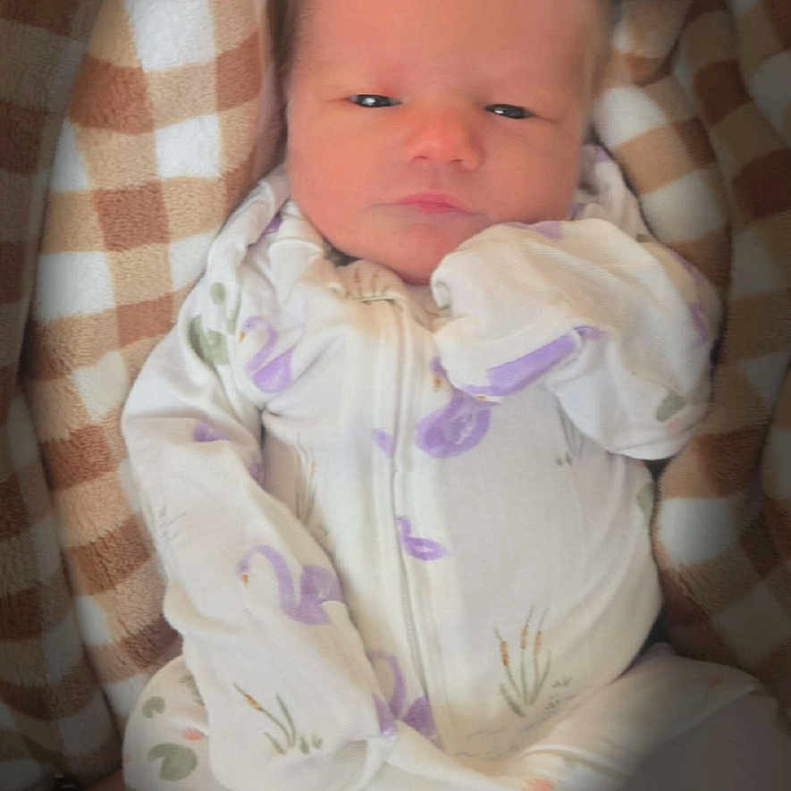 Stevie joined the competition — help win amazing prizes! newborn, baby, blanket, onesie, infant, sleepwear, patterned_clothing, face, person, portrait, cozy, soft, checkered, cute, lying_down, indoor, child, small, cute_baby, resting