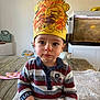 Ilyann participe au concours pour gagner de l'argent avec cette photo : toddler, child, paper_crown, lion_mask, striped_shirt, table, blanket, indoor, fish_tank, curious, portrait, baby, hand, face, person, clothing, home, furniture, cute, sitting