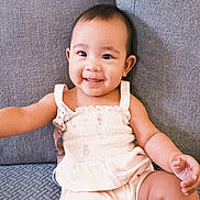Yumi joined the competition — help win amazing prizes! arm, baby, child, comfort, couch, cute, dress, expression, face, furniture, happy, indoor, infant, leg, person, portrait, sitting, skin, smiling, young