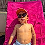 blue_shorts, bright, cap, casual, child, daytime, fence, leisure, outdoor, person, relaxing, shirtless, skin, summer, sunbathing, sunglasses, sunlight, towel, vacation, young