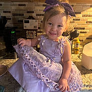 Elaina joined the competition — help win amazing prizes! toddler, child, dress, lavender, bow, headband, smile, kitchen, counter, tile_backplash, utensils, milk_carton, happy, clothing, portrait, indoors, person, cute, baby, playful