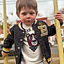 Jaxson joined the competition — help win amazing prizes! child, boy, jacket, sweater, bear_graphic, outdoor, playground, yellow_bars, clothing, face, person, casual_wear, expression, daylight, young, portrait, holding, hands, background_blur, urban