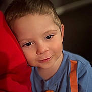 Jaxson joined the competition — help win amazing prizes! child, face, portrait, smile, blue_shirt, orange_stripes, red_cushion, young_boy, indoors, soft_lighting, close_up, curly_hair, happy, cute, skin, person, casual_clothing, resting, head_tilt, warm_colors