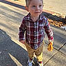 Jaxson is registered to the contest to win money with this photo: child, boy, plaid_shirt, khaki_pants, sneakers, sidewalk, autumn, leaves, shadow, outdoor, daylight, curious, standing, casual_clothing, urban, street, person, young, holding, nature