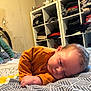 Malo participe au concours pour gagner de l'argent avec cette photo : baby, bed, blanket, child, clothes, cozy, furniture, hand, head, home, indoor, infant, orange_clothing, patterned_bedspread, peaceful, portrait, relaxation, room, shelf, sleeping