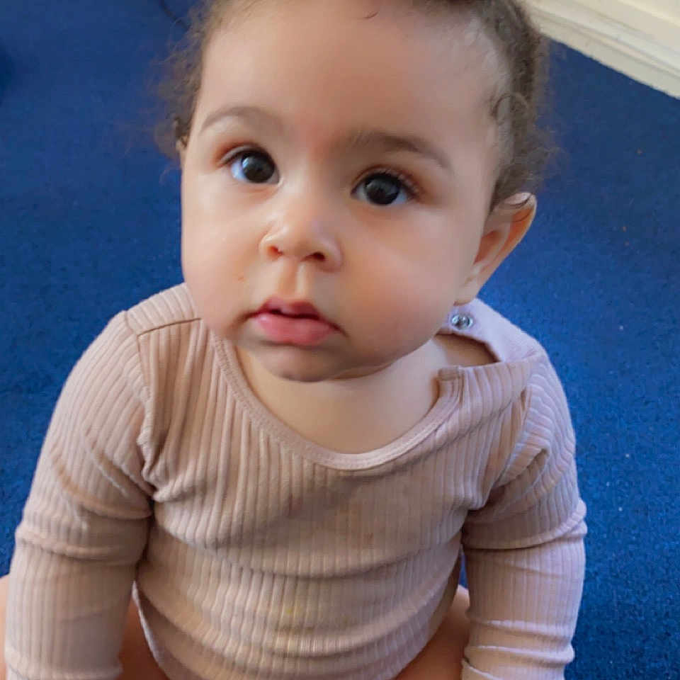 Milarose joined the competition — help win amazing prizes! baby, blue_carpet, child, console, cross_legged, curious, cute, fingertips, hair_tie, home, indoors, infant, long_sleeve_shirt, person, pink_flower, sitting, skin, television, toes, wide_eyes