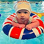 baby, infant, swim_cap, inflatable_ring, pool, water, child, floating, blue_water, red_white_blue, swimming, young_child, face, hands, summer, indoor_pool, cute, closeup, swim_school, gaze