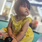 Elizabeth joined the competition — help win amazing prizes! toddler, child, yellow_dress, pool_table, billiard_ball, indoor, curly_hair, sitting, playing, soft_lighting, modern_ceiling, hand, face, portrait, casual, cute, young_child, curious, closeup, daylight