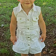 Kaya joined the competition — help win amazing prizes! child, toddler, outdoor, grass, dirt, white_dress, headband, flower, sneakers, smiling, person, nature, greenery, sunlight, portrait, standing, happy, casual_clothing, baby, cute
