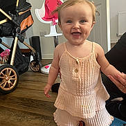 Layla is registered to the contest to win money with this photo: child, toddler, smiling, indoors, floor, toy, stroller, high_chair, wooden_floor, person, clothing, hand, pigtails, happy, baby, play, support, room, door, window