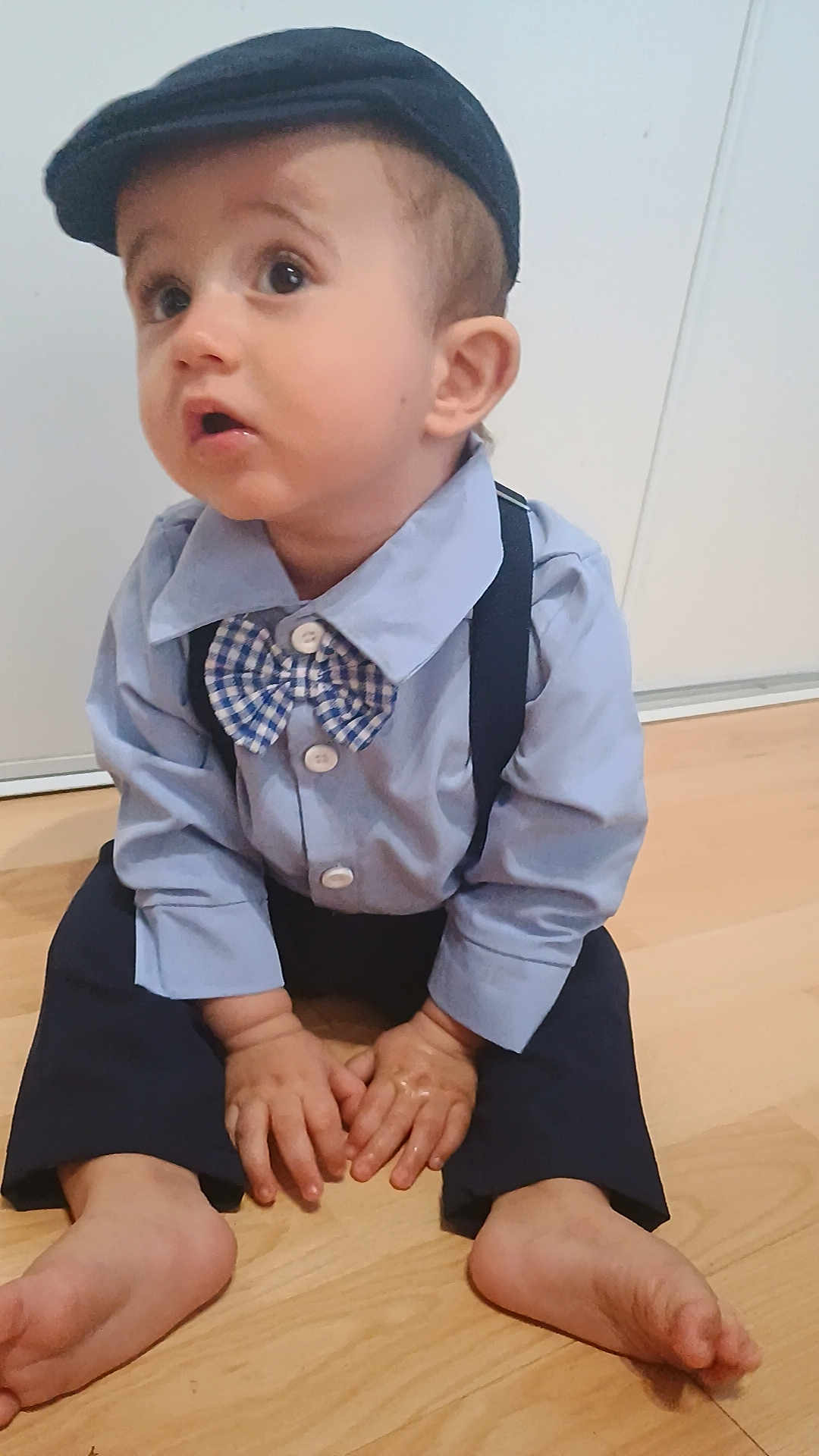 Eliott a rejoint le concours — aidez-le/la à gagner de superbes lots ! toddler, child, boy, barefoot, blue_shirt, bow_tie, suspenders, hat, cap, floor, wooden_floor, sitting, indoors, cute, curious, hands, feet, portrait, clothing, face