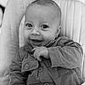 élias participe au concours pour gagner de l'argent avec cette photo : baby, black_and_white, buttons, child, closeup, corduroy, cozy, cushion, expression, eyes, face, hand, happy, infant, jacket, person, portrait, seat, smile, young