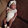 Ja'Zyiah is registered to the contest to win money with this photo: baby, newborn, infant, onesie, headband, white, booties, couch, brown, fabric, comfortable, relaxed, person, child, cute, portrait, indoors, soft, small, resting