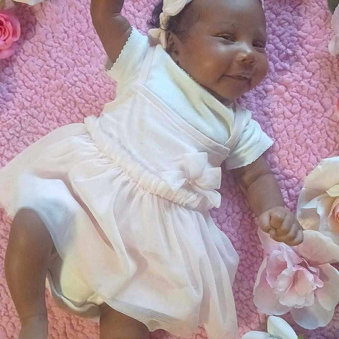 Ja'Zyiah joined the competition — help win amazing prizes! baby, infant, smiling, white_dress, headband, pink_blanket, artificial_flowers, laying_down, hand_raised, happy, cute, child, person, soft_texture, indoors, portrait, decorative_flowers, small_child, baby_girl, celebration