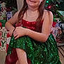 child, christmas_tree, decorations, festive, floor, gift_bags, girl, happy, headband, holiday, holiday_lights, indoors, long_hair, presents, red_bow, seated, shoes, smiling, sparkly_dress, wooden_floor