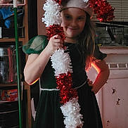 Taylor joined the competition — help win amazing prizes! candy_cane, cheerful, child, decoration, dress, festive, girl, green_dress, hand_on_hip, holiday, holiday_decoration, home, indoor, kitchen, long_hair, person, posing, smile, tinsel, young_person