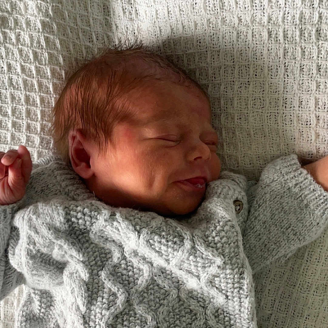 Bailey is registered to the contest to win money with this photo: baby, bed, blanket, bodypart, clothing, coat, face, finger, furniture, glove, hand, head, knitwear, newborn, person, photography, portrait, quilt, sleeping, sweater