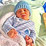 baby, bed, blanket, blue, cozy, cute, green, hand_holding, hat, hospital_bed, infant, knit_hat, newborn, peaceful, person, resting, sleeping, small_hands, soft_texture, striped_clothing
