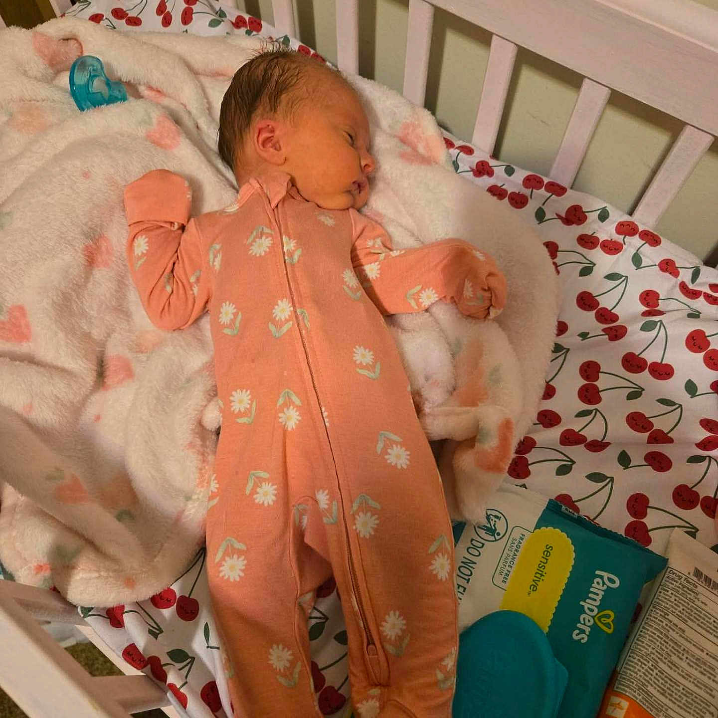 Naomi is registered to the contest to win money with this photo: baby, newborn, sleeping, crib, blanket, onesie, baby_wipes, lotion, soft_toys, cherry_pattern, infant, bed, bedroom, sleep, cute, peaceful, child, person, rest, baby_care