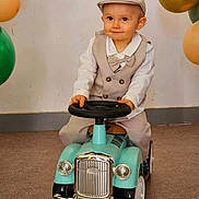 Auxence a rejoint le concours — aidez-le/la à gagner de superbes lots ! toddler, child, toy_car, balloons, indoor, carpet, vintage, beige_clothing, bow_tie, cap, play, cute, smile, portrait, hands, floor, wheel, celebration, party, happy