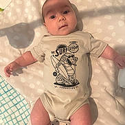 Elijah joined the competition — help win amazing prizes! baby, infant, onesie, clothing, blanket, pattern, face, skin, arms, legs, cute, lying_down, indoor, child, person, expression, head, photography, soft_lighting, comfort