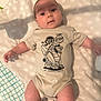 baby, infant, onesie, clothing, blanket, pattern, face, skin, arms, legs, cute, lying_down, indoor, child, person, expression, head, photography, soft_lighting, comfort