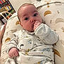 baby, infant, blanket, clothing, face, hand, pillow, indoor, person, child, furniture, home, pattern, sleeve, cozy, cute, curious, lying_down, animal_print, nursery