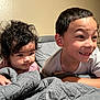 child, children, bedroom, blanket, curly_hair, smiling, happy, indoors, portrait, siblings, young, cute, candid, face, person, home, playful, expression, pajamas, relaxed