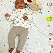 Ayana a rejoint le concours — aidez-le/la à gagner de superbes lots ! baby, babylaughing, blanket, clothing, face, happy, head, infantbed, pants, person, sitting, sleeve, smile