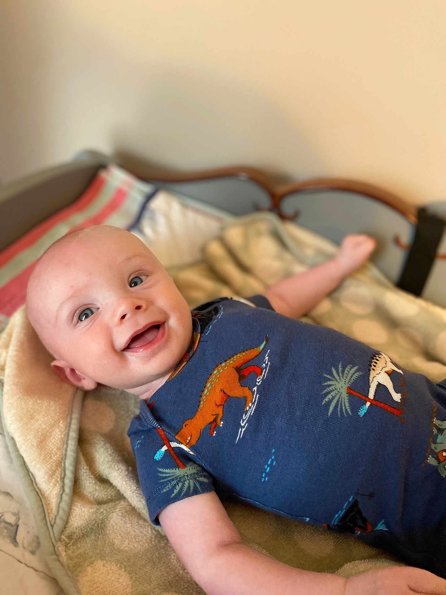 Asher joined the competition — help win amazing prizes! baby, infant, smile, happy, onesie, blue_clothing, dinosaur_print, blanket, cozy, indoor, person, child, cute, laying_down, head, face, skin, expression, young, portrait