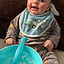baby, smiling, bib, blue, onesie, baby_food, bowl, spoon, sitting, cushion, brown, cute, infant, food, feeding, happy, child, indoors, clothing, portrait