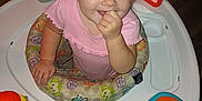 Lenox is registered to the contest to win money with this photo: activity_center, baby, blue_eyes, child, colorful, cute, face, floor, hand, happy, indoor, infant, person, pigtails, pink_clothing, playtime, smiling, toy, walker, young_child