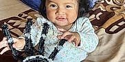Zoemy is registered to the contest to win money with this photo: baby, child, infant, person, face, hair, pony_tail, bed, blanket, toy, spider, hand, foot, skin, clothing, indoor, curious, smile, decor, playful