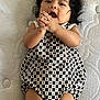 Zoemy joined the competition — help win amazing prizes! baby, child, infant, mattress, patterned_clothing, romper, hands, face, curly_hair, lying_down, cute, young_child, skin, indoors, expression, playful, black_hair, small_person, texture, comfort
