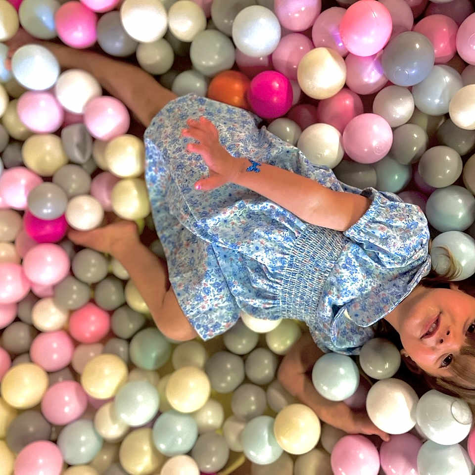 Rennayah-Renae is registered to the contest to win money with this photo: ball_pit, balls, blue_dress, child, childhood, colorful, curious, face, floral_pattern, fun, hair, happy, indoor, lying_down, pastel_colors, play, play_area, relaxed, skin, toy