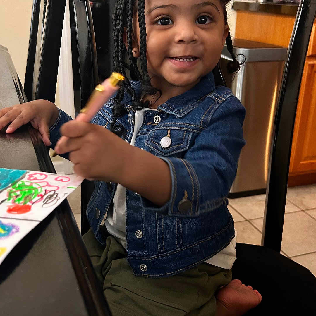 Jasmine is registered to the contest to win money with this photo: blackhair, bodypart, child, clothing, face, female, finger, furniture, girl, hair, hand, happy, head, pants, person, photography, portrait, sitting, smile, table