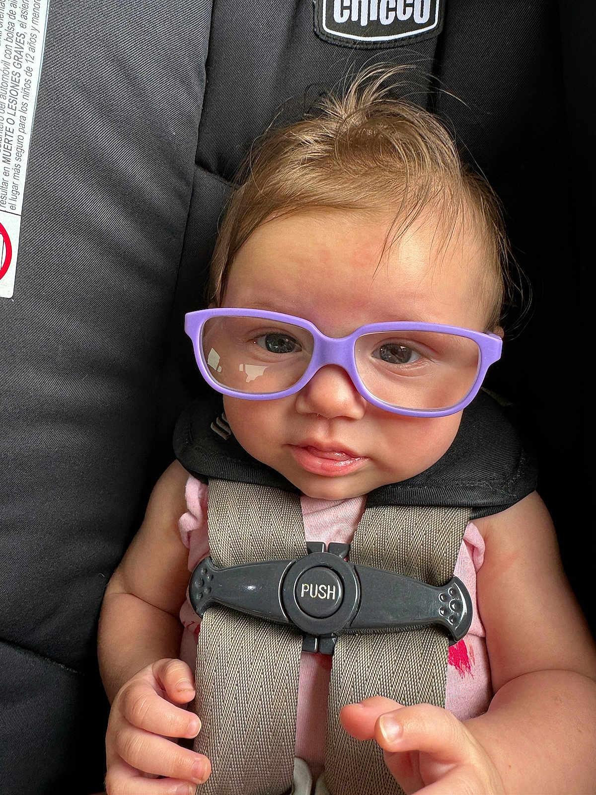 Kennedie joined the competition — help win amazing prizes! baby, child, glasses, car_seat, harness, purple_glasses, infant, cute, face, hand, clothing, safety, seatbelt, straps, curly_hair, indoor, person, portrait, closeup, expression