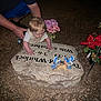 Hunter joined the competition — help win amazing prizes! baby, adult, gravestone, flowers, night, flash, hands, ground, bluebird_figurines, memorial, headstone, person, clothing, skin, outdoor, nature, rock, plant, cemetery, tender_moment