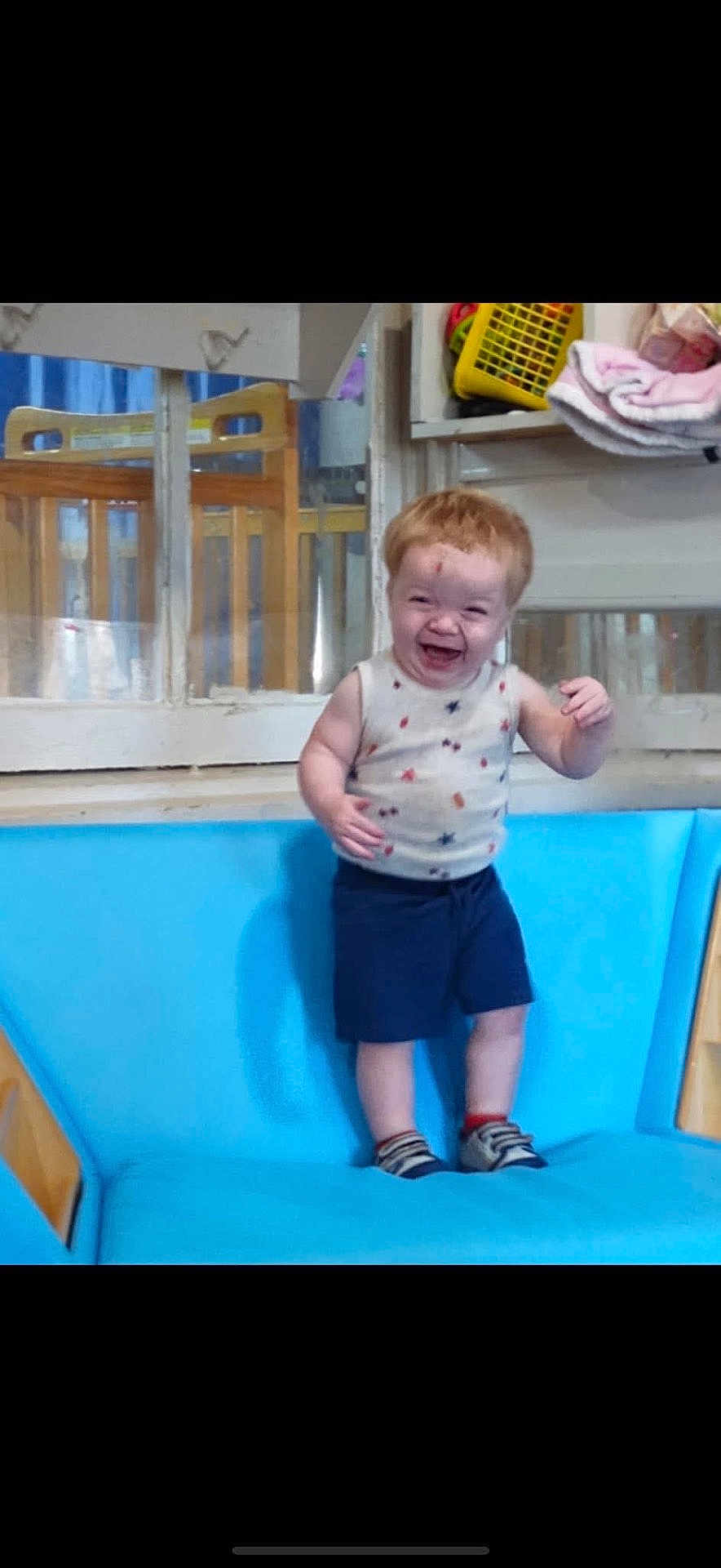 Hunter joined the competition — help win amazing prizes! child, toddler, smiling, indoor, couch, blue_couch, shorts, sleeveless_shirt, happy, standing, furniture, wooden_chair, window, socks, shoes, person, playful, home, room, casual_clothing