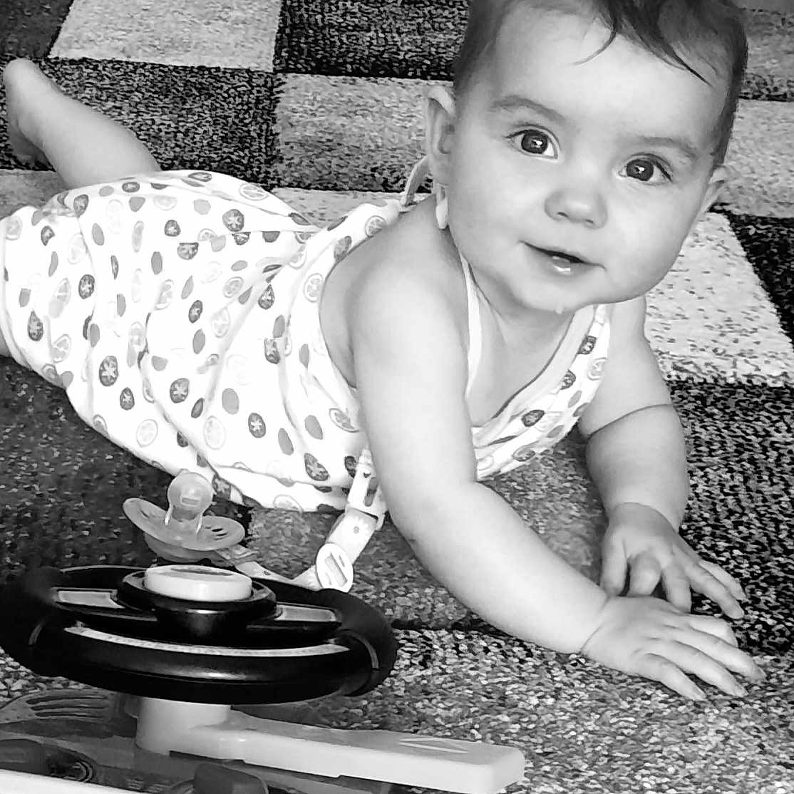 ïvi a rejoint le concours — aidez-le/la à gagner de superbes lots ! baby, black_and_white, carpet, child, clothing, cute, expression, eyes, face, floor, hand, indoor, infant, pattern, person, play, smiling, steering_wheel, toddler, toy