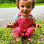 toddler, child, curly_hair, pink_overalls, flower, daisy, grass, outdoor, road, nature, greenery, smiling, happy, portrait, cute, eyes, face, clothing, person, daylight