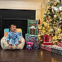 Deava is registered to the contest to win money with this photo: toddler, child, pajamas, chair, laughing, christmas_tree, christmas_lights, presents, gift_bags, plush_toy, flooring, holiday_decor, ornaments, festive, indoor, home, joyful, celebration, smiling, cozy