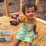 Deava joined the competition — help win amazing prizes! toddler, child, smiling, dress, yellow, curly_hair, screws, tools, construction, wood_floor, box, glove, drill, outdoor, happy, person, playful, building, sitting, daylight