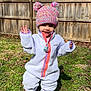 Deava is registered to the contest to win money with this photo: toddler, child, fleece, hat, pom_poms, outdoor, grass, wooden_fence, smiling, waving, boots, winter_clothing, sunny_day, nature, person, baby, playful, cute, cold_weather, knit_hat