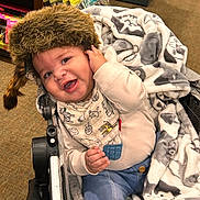 Oko joined the competition — help win amazing prizes! baby, child, smiling, stroller, blanket, fur_hat, indoor, toy_store, clothing, happy, portrait, infant, cute, warm, seated, colorful, accessory, fabric, comfort, playful
