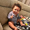 Oko joined the competition — help win amazing prizes! baby, child, smiling, curly_hair, couch, indoor, snack, toy, colorful, pillow, happy, person, sitting, cute, infant, clothing, face, hand, foot, relaxed