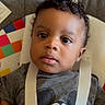 Noa joined the competition — help win amazing prizes! baby, child, infant, portrait, face, curly_hair, gray_shirt, cartoon_character, baby_seat, straps, colorful_background, indoor, young_child, cute, looking_at_camera, closeup, person, head_and_shoulders, soft_lighting, casual_clothing